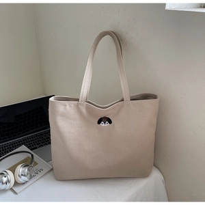 Detail of canvas tote bag showing beige texture and cute puppy head embroidery