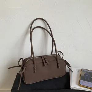 Détail du sac à bandoulière marron mat avec double fermeture éclair et nœuds décoratifs
