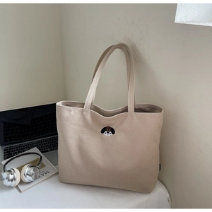Detail of beige canvas tote bag with cute dog embroidery and long shoulder straps