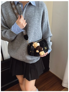 Détail du sac bandoulière en velours noir avec sangle tissée et breloque ourson