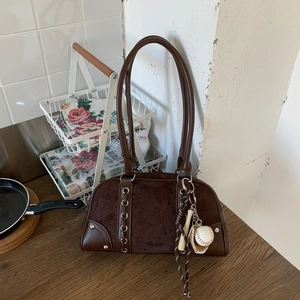 Close-up of brown frosted leather boston bag with baseball charm and metallic eyelets