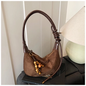 Close-up of retro brown suede crescent bag with rope handle and decorative beads