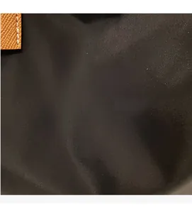 Detailed view of durable black nylon fabric and brown litchi grain leather trim on tote bag