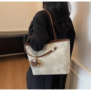 Detail of marble texture tote bag with brown leather straps and plush monster charm