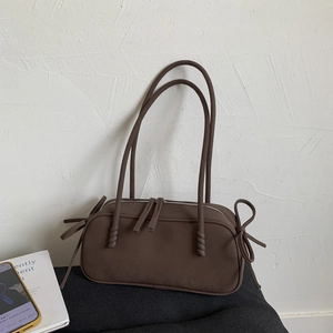 Détail d'un sac à main marron foncé mat avec double fermeture éclair et nœuds décoratifs