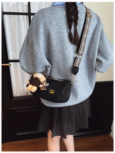 Détail du sac oreiller noir avec broderie CHUU jaune et breloque en peluche d'ours