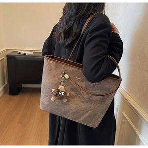 Detail of large tote bag with brown marble texture, metal hardware and plush charm accessory