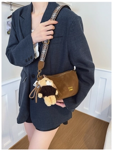 Détail du sac oreiller en daim avec bandoulière jacquard et breloque ours en peluche