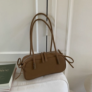 Détail du sac à bandoulière marron avec cordon à nœud sur un canapé blanc