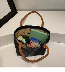 Spacious interior of black nylon tote bag showing tablet, phone and cosmetics storage