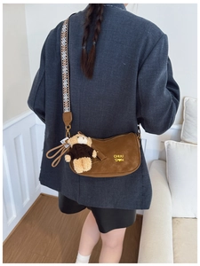 Détail d'un sac demi-lune en daim marron avec pendentif ours et bandoulière géométrique