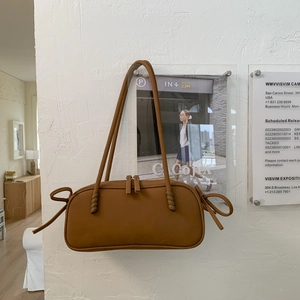 Gros plan détaillé d'un sac cabas marron avec nœuds décoratifs et double fermeture éclair