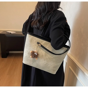 Detailed texture of grey marble tote bag featuring black trim and plush monster charm