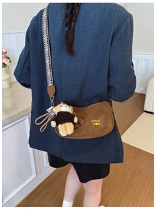 Sacoche en daim marron avec bandoulière ethnique et peluche portée par un mannequin