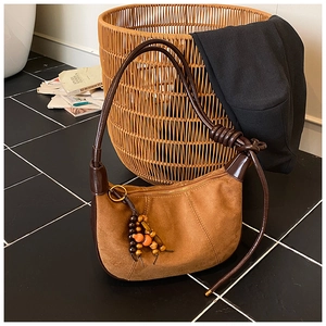 Detail of hobo bag with brown suede texture, leather trim, and beaded tassel charm