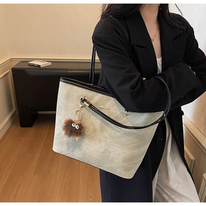 Detail of grey marble pattern tote bag with metal bar and plush monster charm