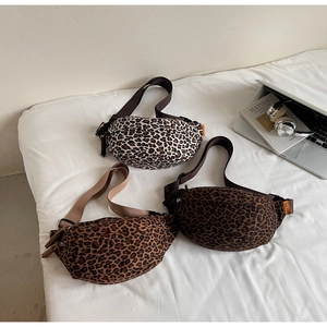 Detailed view of three leopard print cross-body bags in various shades on white bedding
