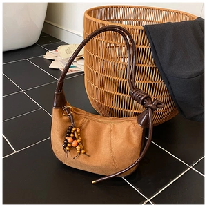 Close-up of caramel suede hobo bag with wood bead pendant and knot strap details