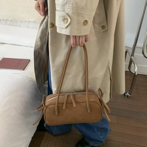 Détail du sac bandoulière marron avec nœud latéral et double fermeture éclair argentée