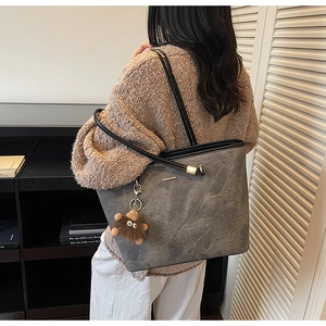 Detail of grey marble texture tote bag with brown plush charm on model shoulder