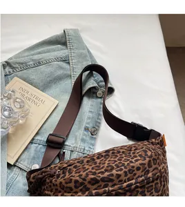 Detail of adjustable nylon strap and plastic buckle on leopard print crossbody bag