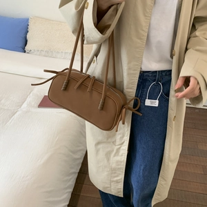 Vue détaillée du sac polochon en cuir mat marron avec ruban latéral et fines bretelles doubles