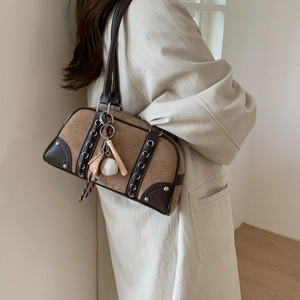 Detail of brown suede shoulder bag with leather lacing and sports charms on model