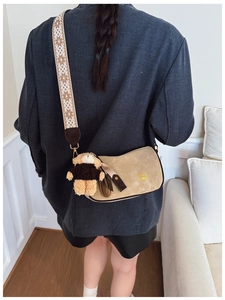 Détail du sac polochon en daim beige avec large bandoulière et breloque ours