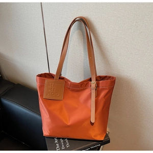 Detail of orange tote bag showing leather strap texture and HAMI ROO designer tag