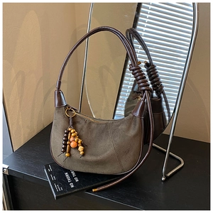 Detailed macro view of the coffee brown suede texture and wooden bead tassels on the bag