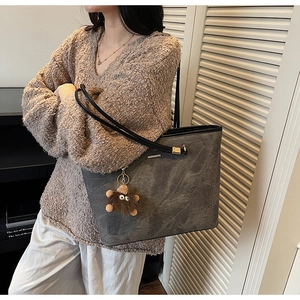 Detail view of large grey marble textured tote bag with a brown fuzzy monster charm