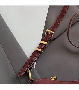 Close-up of wine red leather shoulder strap with adjustable premium gold metal buckle