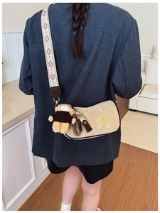 Détail du sac bandoulière en daim beige avec sangle tissée ethnique et pendentif d'ours