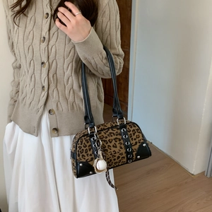 Detail of leopard print handbag with metal eyelets and decorative baseball charm