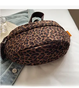 Detail of leopard print crossbody bag featuring brown strap and orange woven side label