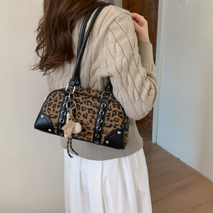 Close-up of leopard print underarm bag with baseball charms and silver eyelet details