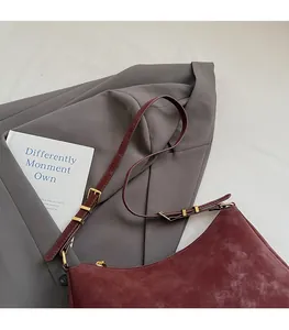 Detail of adjustable leather strap and golden buckle on burgundy retro tote bag