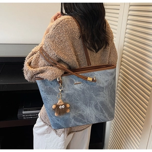 Detail of blue marble texture tote bag with leather handles and plush monster charm