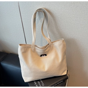 Detailed view of cream canvas tote bag with cute dog head embroidery and long strap