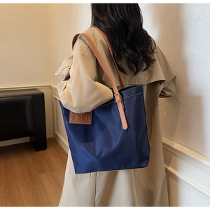 Detail of navy blue nylon tote bag with brown leather straps and HIROO logo patch