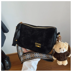 Détail du sac bandoulière en daim noir avec logo doré et sangle ethnique tissée