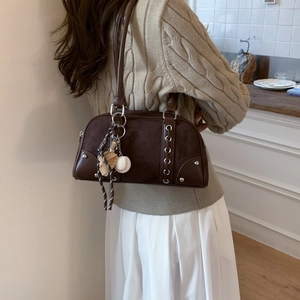 Detail of brown patchwork shoulder bag with silver eyelets and sports charms