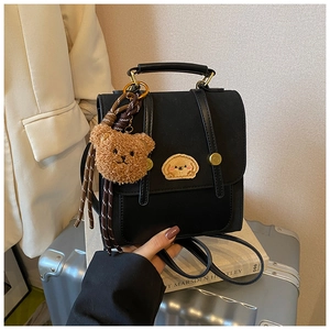 Detail eines schwarzen Lederrucksacks mit Hundestickerei auf einem silbernen Koffer