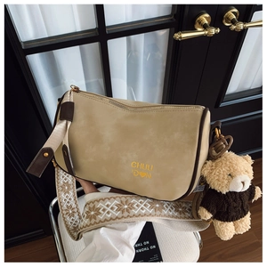 Détail du sac polochon beige avec breloque ours et bandoulière large à motifs