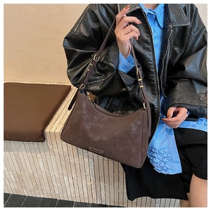 Close-up of a vintage dark brown matte underarm bag worn with a black leather jacket