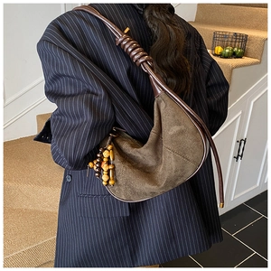 Detail view of brown matte crescent bag with beaded charm and segmented strap on model