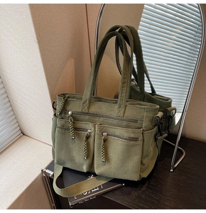 Detailed view of army green corduroy tote bag featuring multiple woven zipper pockets