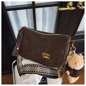 Détail du sac polochon en daim marron avec bandoulière ethnique et peluche d'ours
