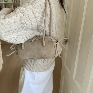 Détail du sac hobo mat abricot avec nœuds en ruban et fermeture à glissière à pompons