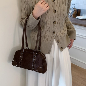 Detail of dark brown suede underarm bag with silver ring studs and twin shoulder straps